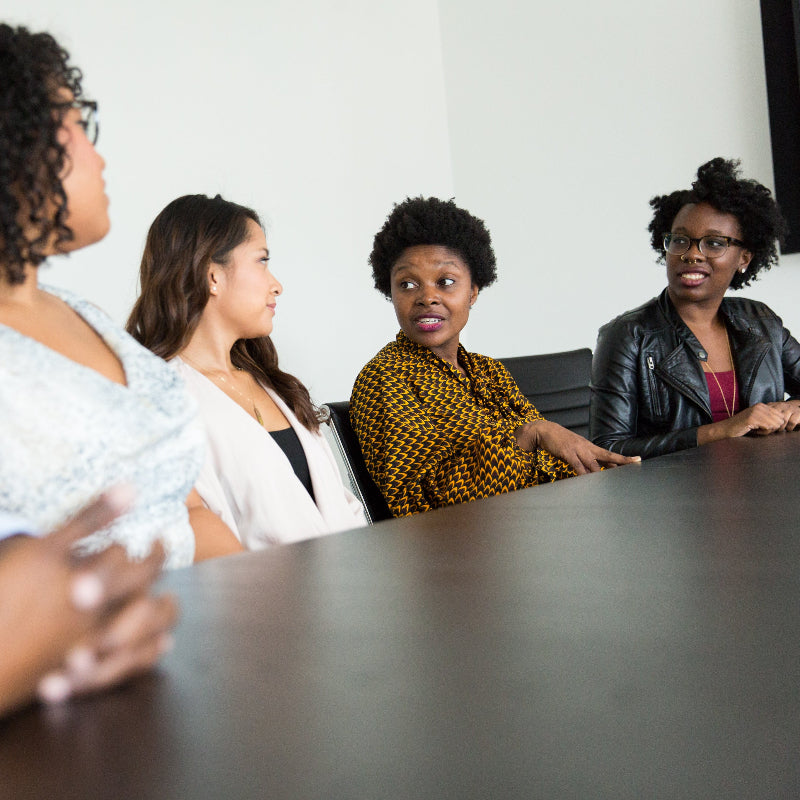 Group of people sitting around a conference table in a meeting setting.