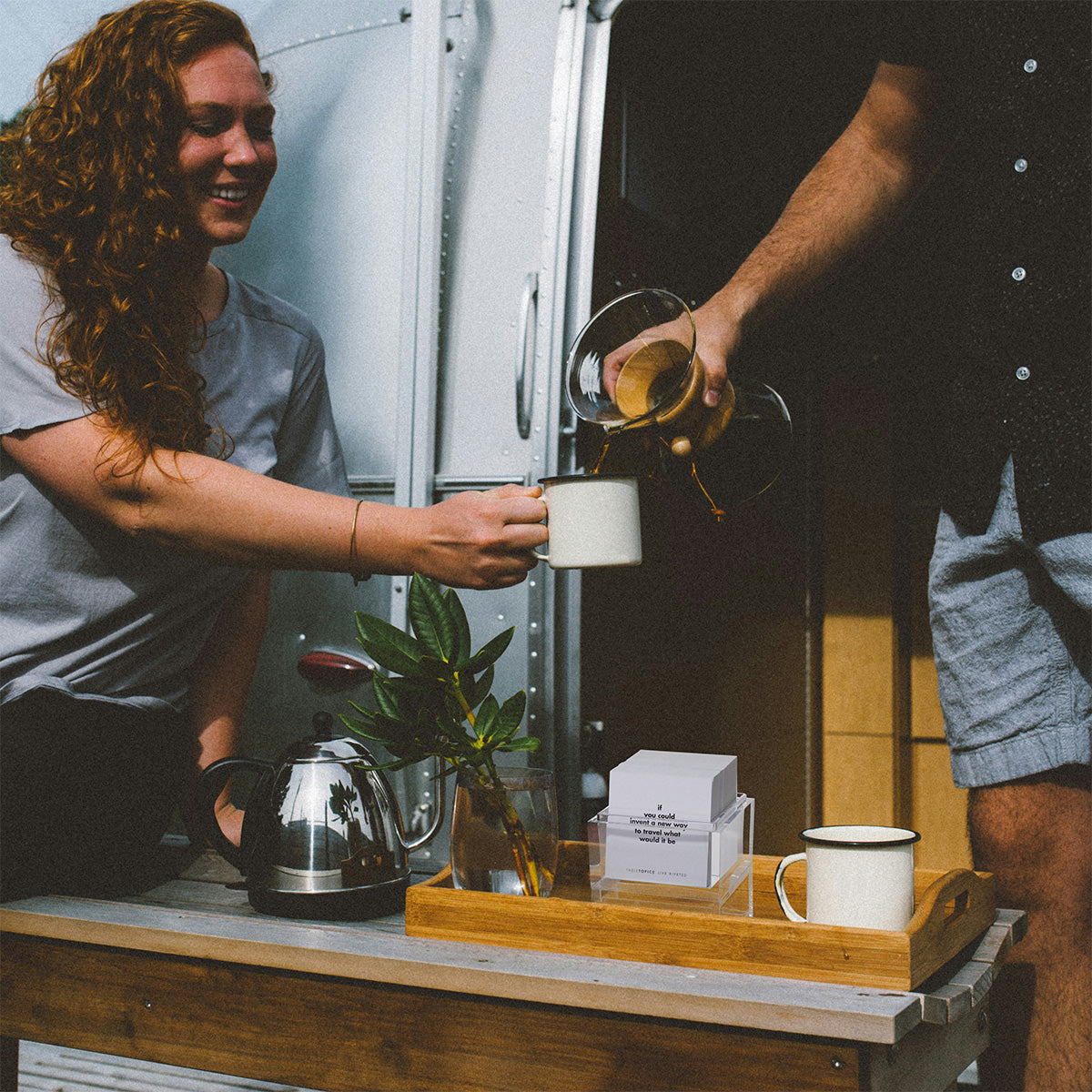 Couple taking a break from travelling with TableTopics Airstream Live Riveted Conversation Cards