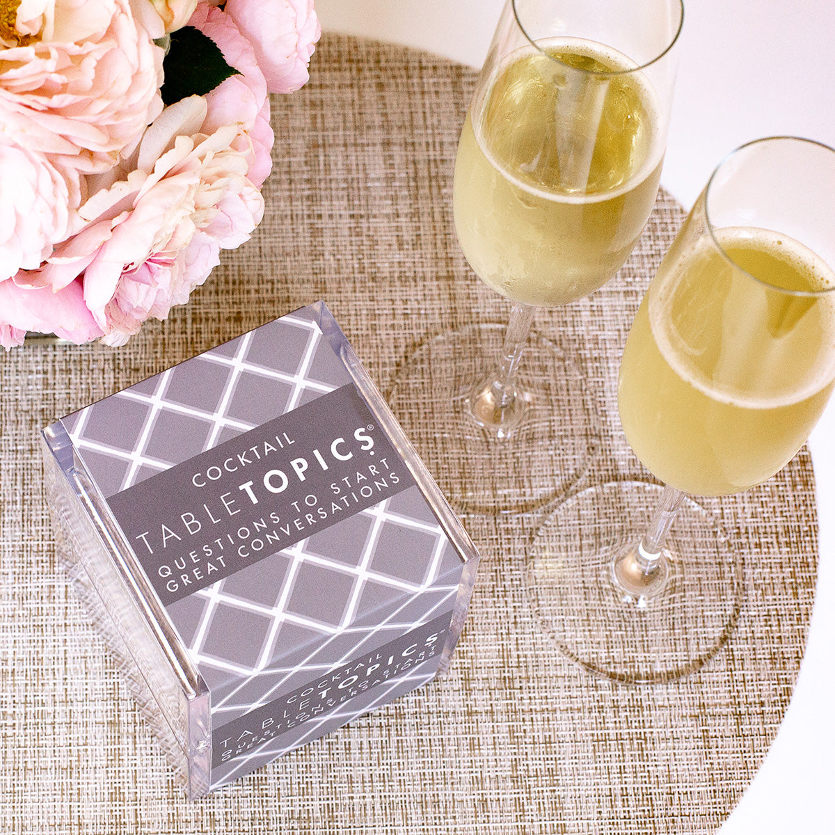 TableTopics Cocktail set next to two glasses of champagne