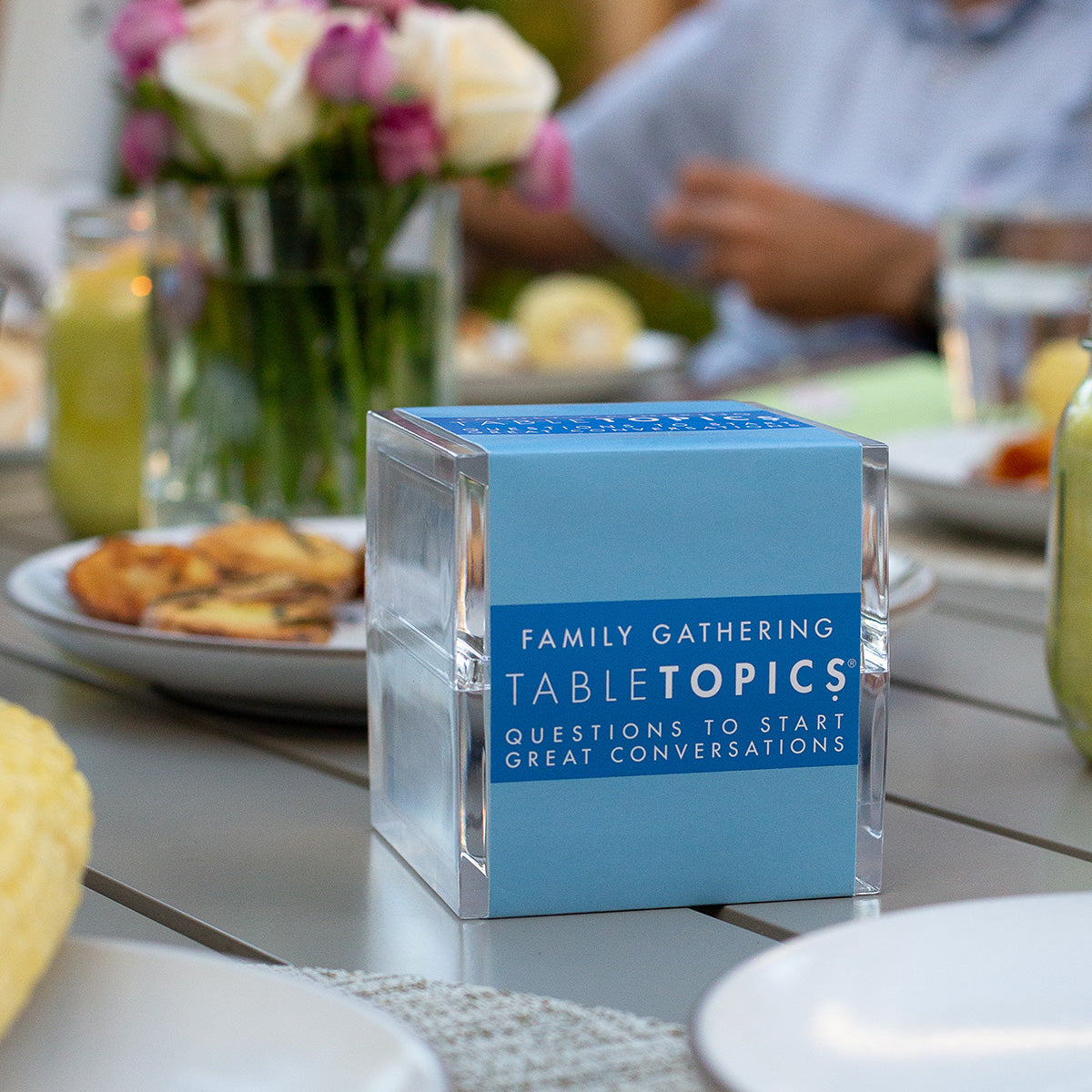 TableTopics Family Gathering on a dinner table with people, food, and flowers in the background