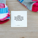 TableTopics Family conversation card on the floor with crumpled socks. The card reads, "Which household chores do you like and which do you try to avoid?"