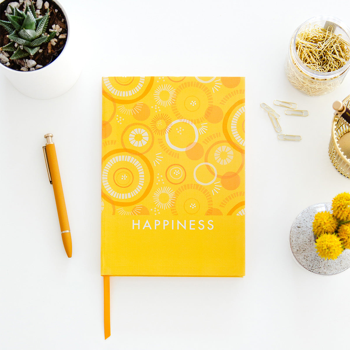 TableTopics Happiness Prompted Journal closed on a desk with pen and plant