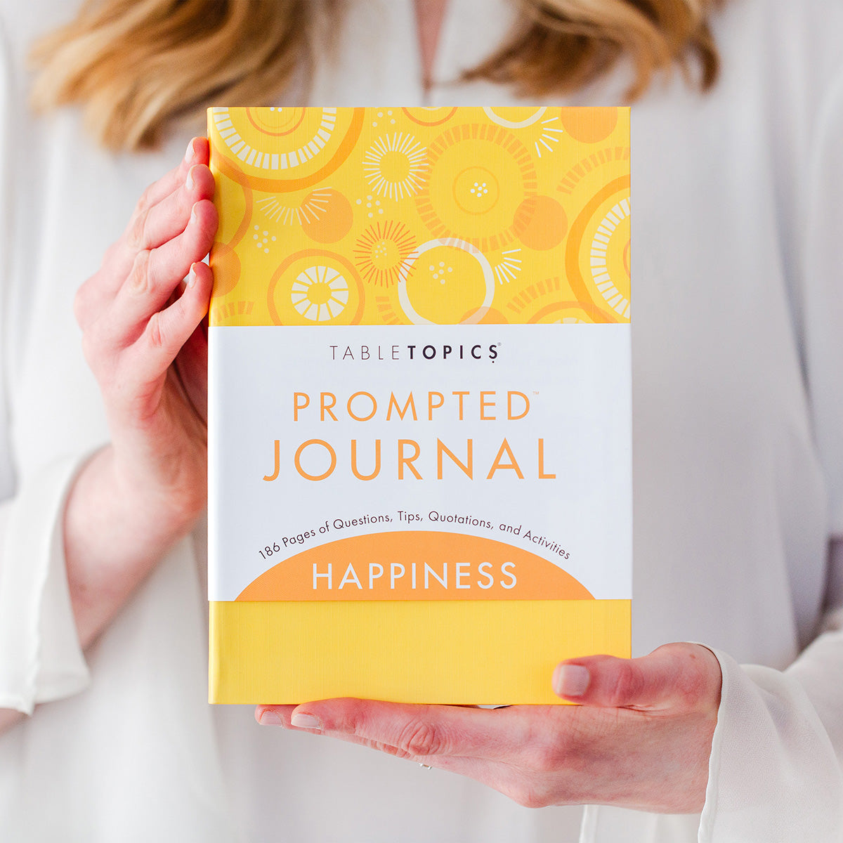 Woman holding TableTopics Happiness Prompted Journal