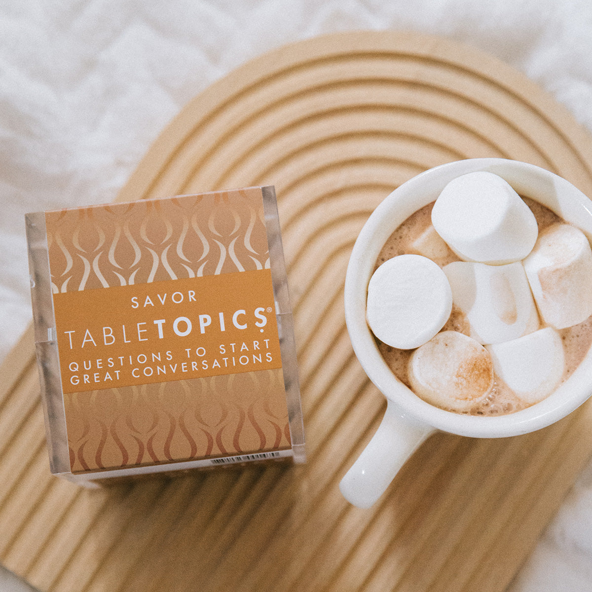 TableTopics Savor conversation starter setr next to a cup of cocoa with huge marshmallows