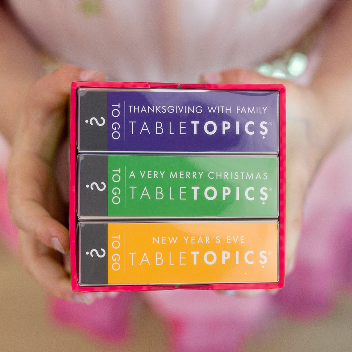 Girl holding TableTopics conversation card set featuring different holidays - Thanksgiving, Christmas, and NYE