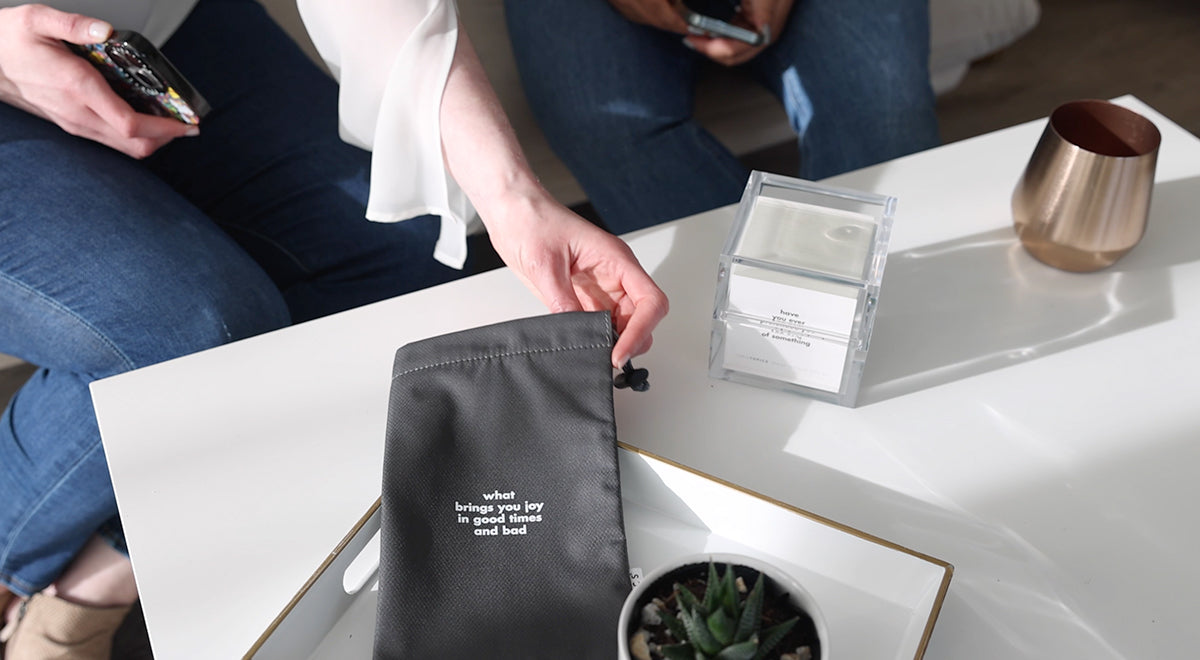 Table with TableTopics Happiness and hands putting phones into a Phone Away Bag