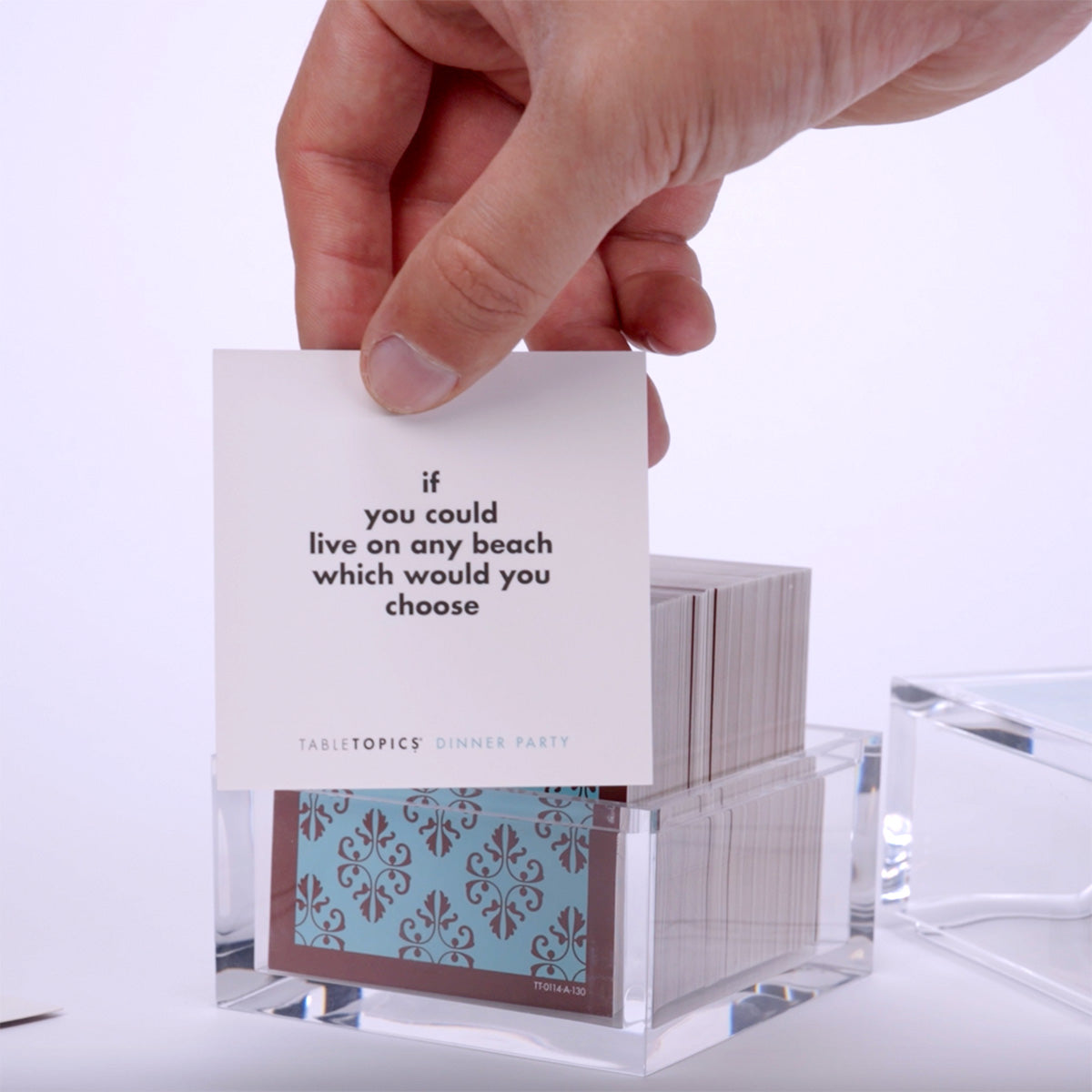 Hand pulling out TableTopics Dinner Party cards from the container and showing the questions