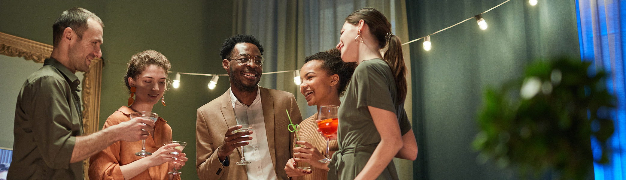 Five people standing in a living room holding cocktails