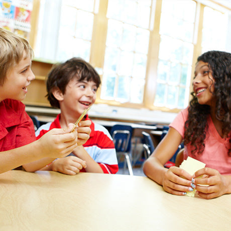 Four elementary school students playing TableTopics Family in their classroom