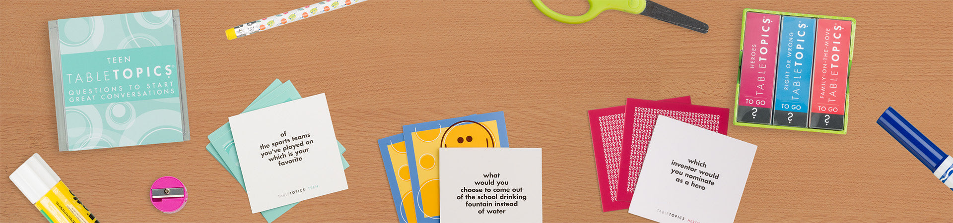 TableTopics Teen, Kids, and Family Conversation Pack cards on a desk with some school supplies.