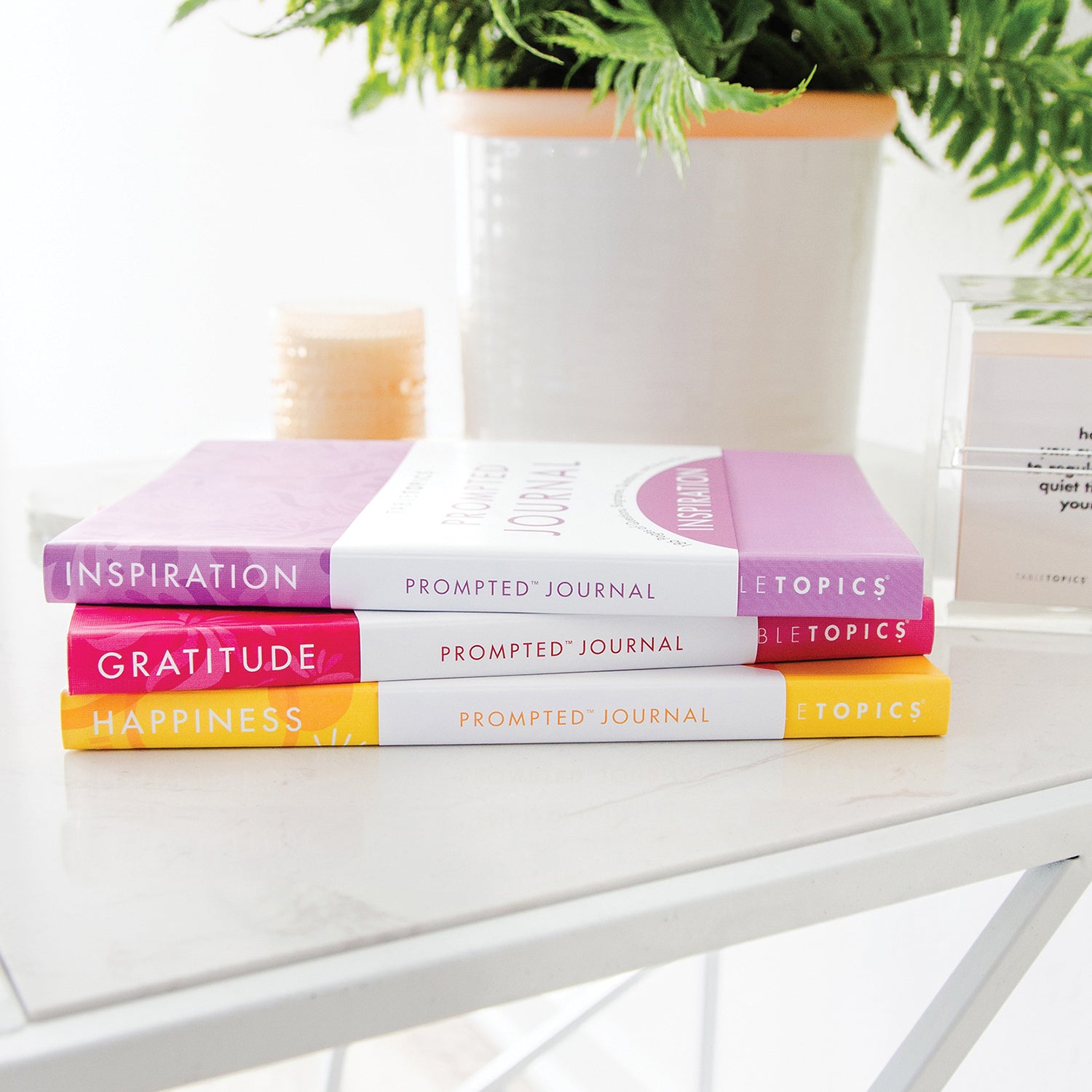 3 TableTopics journals on a side table with a conversation starter cube off to the side