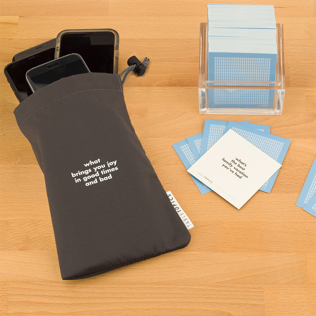 TableTopics Family Gathering Conversation Starter Set and Phone Away Bag with phones in it on a table