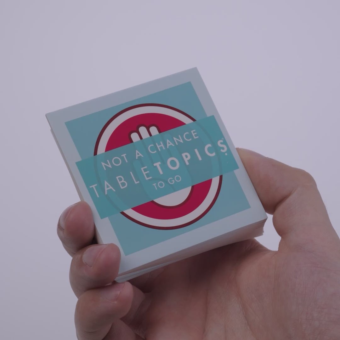 Hand pulling out TableTopics Not a Chance cards from the container and showing the questions