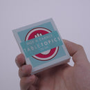 Hand pulling out TableTopics Not a Chance cards from the container and showing the questions