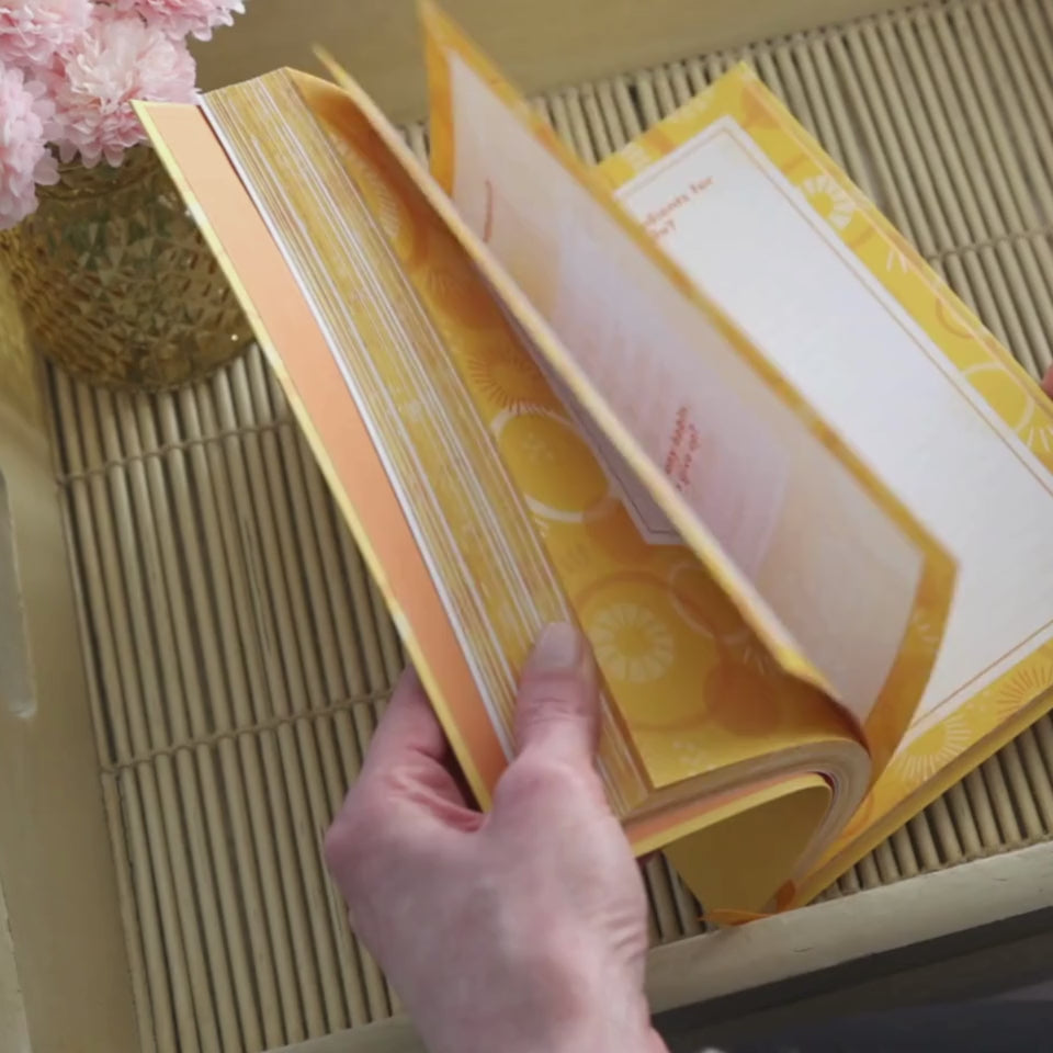 Hands flipping through the pages of the Happiness Prompted Journal