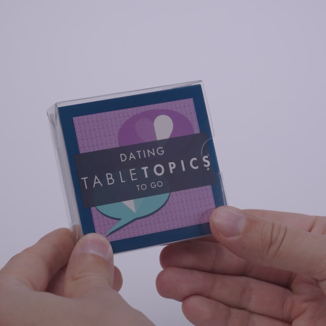Hand pulling out TableTopics Dating conversation cards from the container and showing the questions