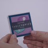 Hand pulling out TableTopics Dating conversation cards from the container and showing the questions
