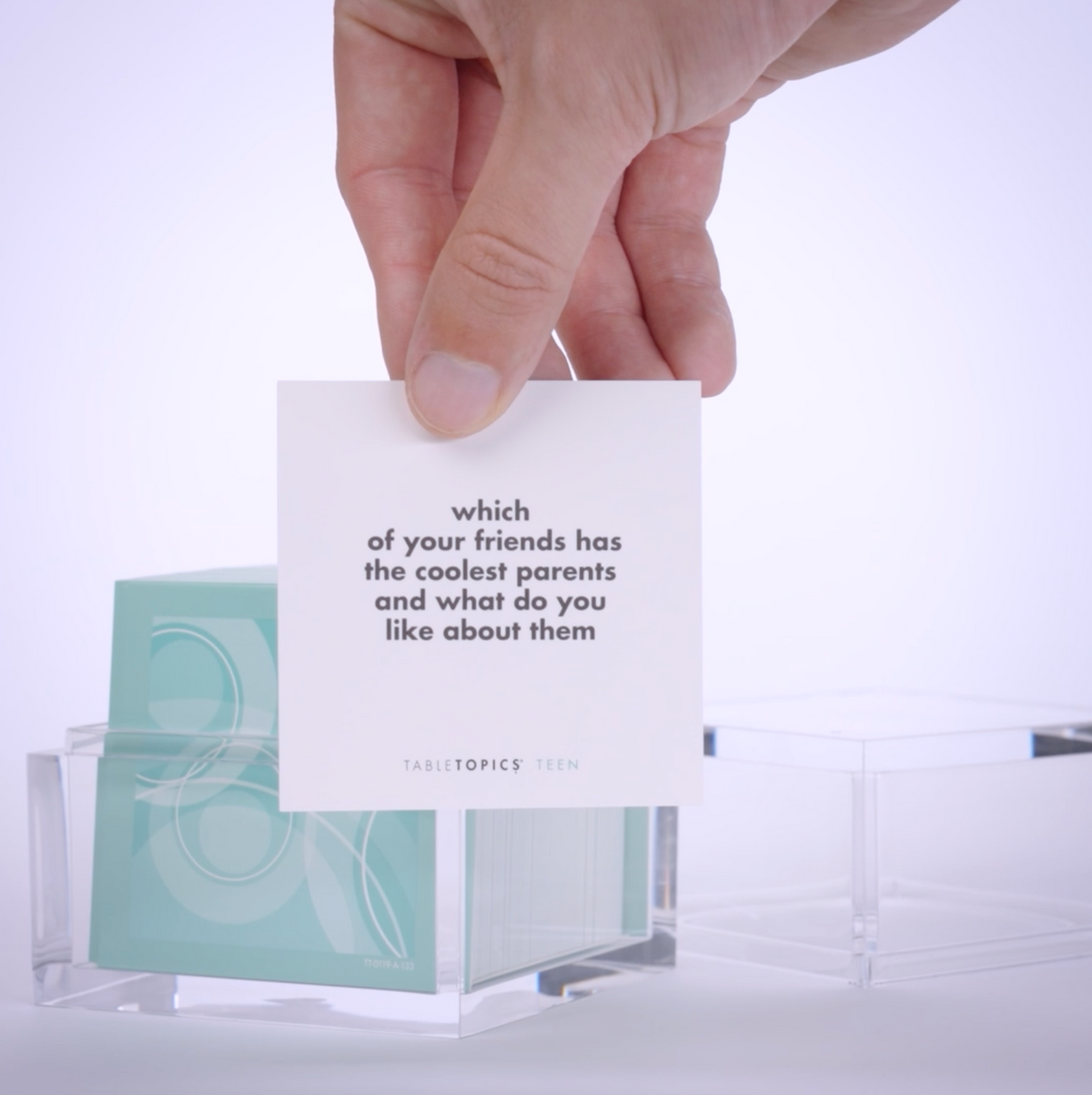 Hand pulling out TableTopics Teen conversation cards from the container and showing the questions