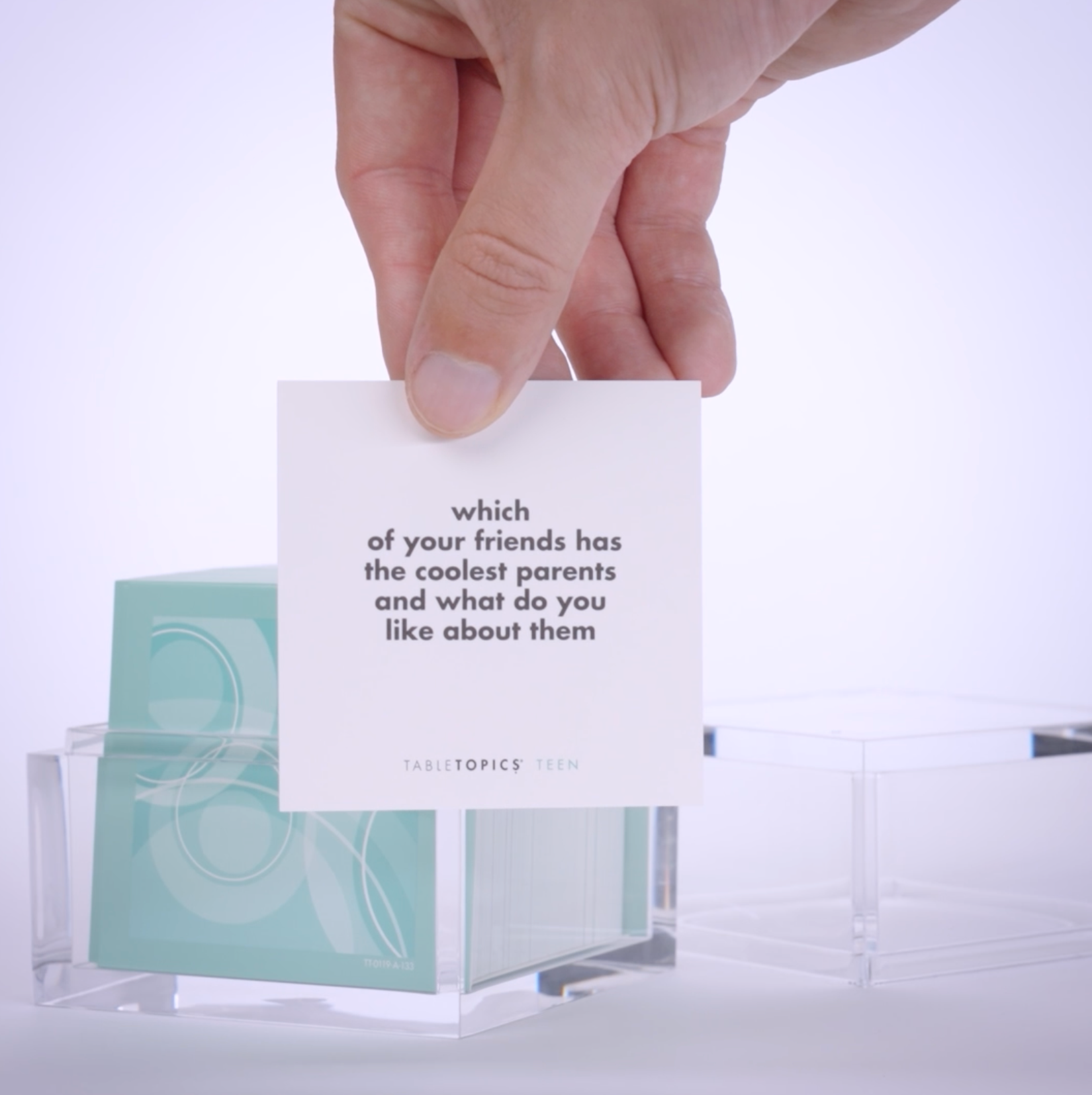 Hand pulling out TableTopics Teen conversation cards from the container and showing the questions