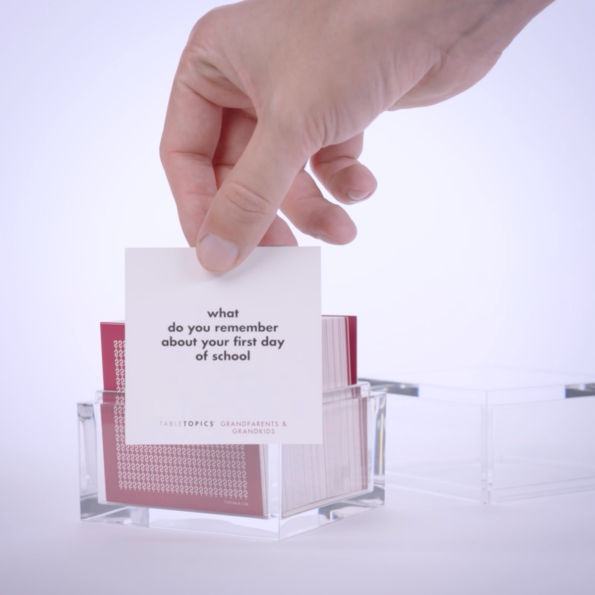 Hand pulling out TableTopics Grandparents & Grandkids conversation cards from the container and showing the questions