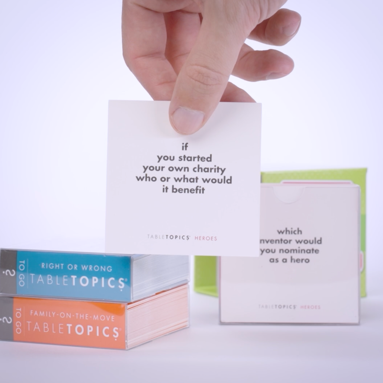 Hand pulling conversation cards from TableTopics Family Conversation Pack and showing the questions