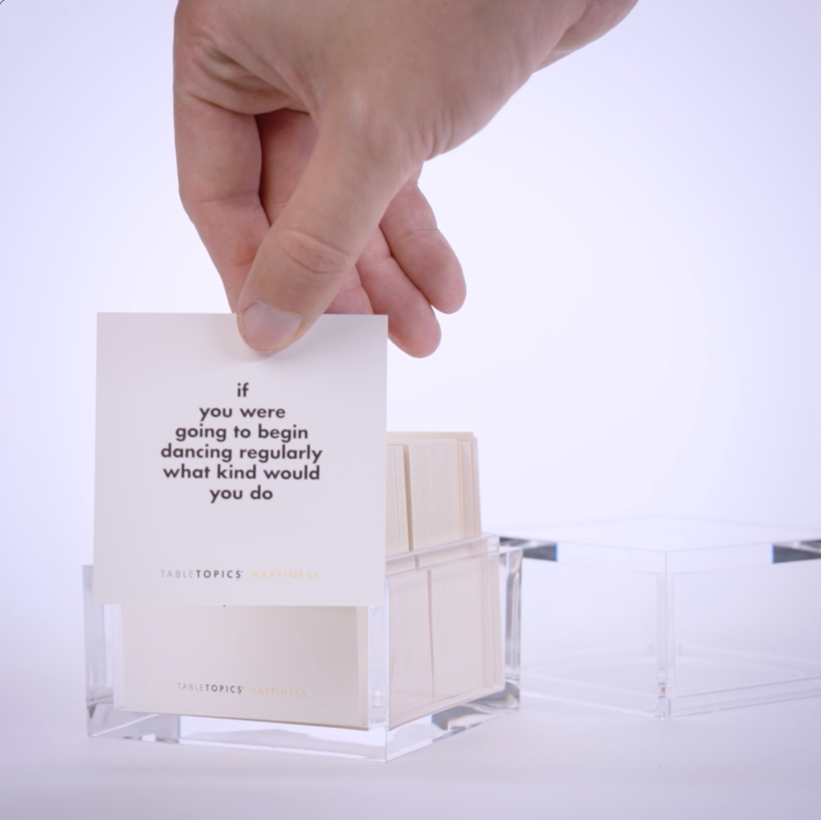 Hand pulling conversation cards from TableTopics Happiness and showing the questions