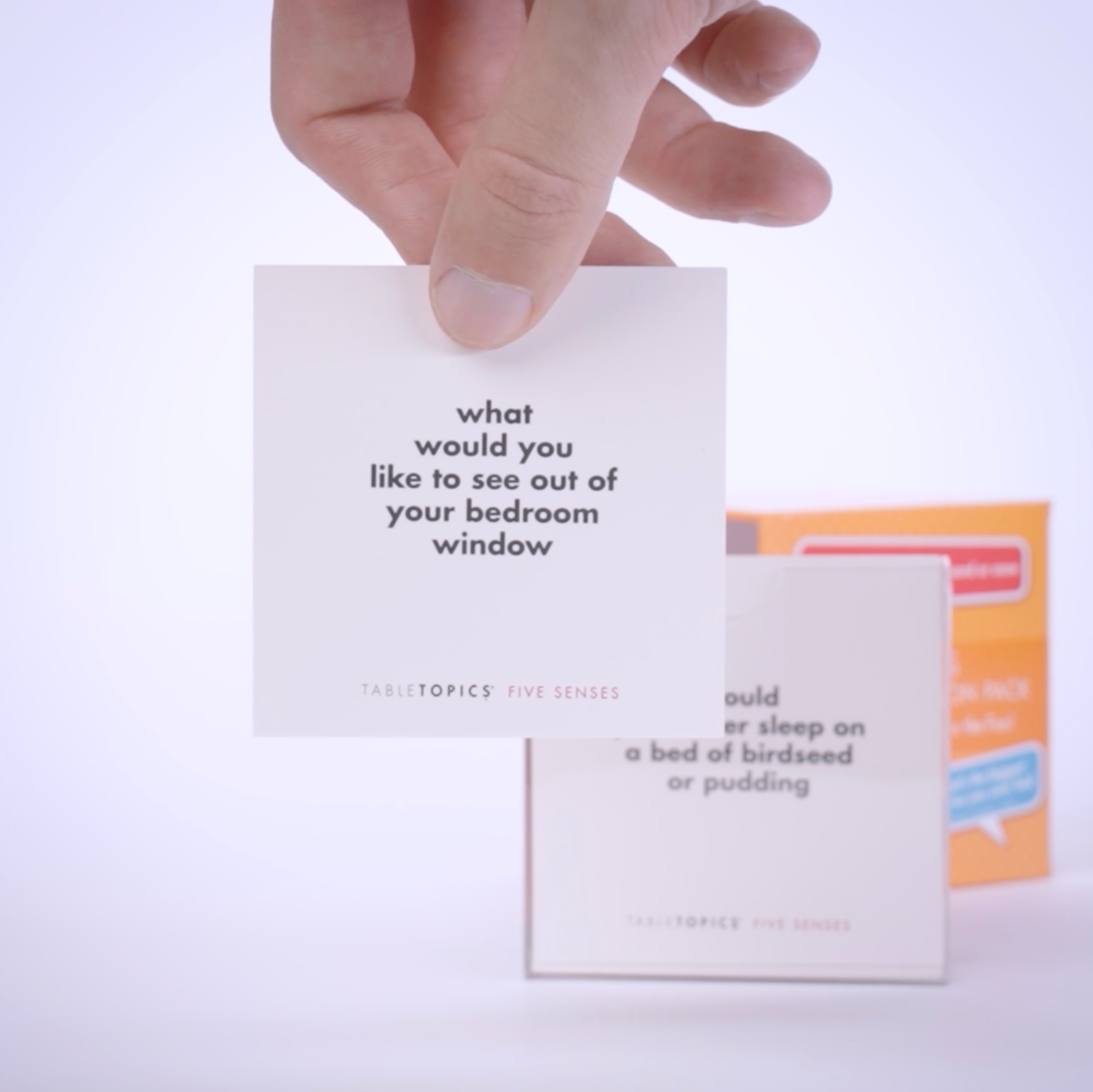 Hand pulling conversation cards from TableTopics Kids Conversation Pack and showing the questions