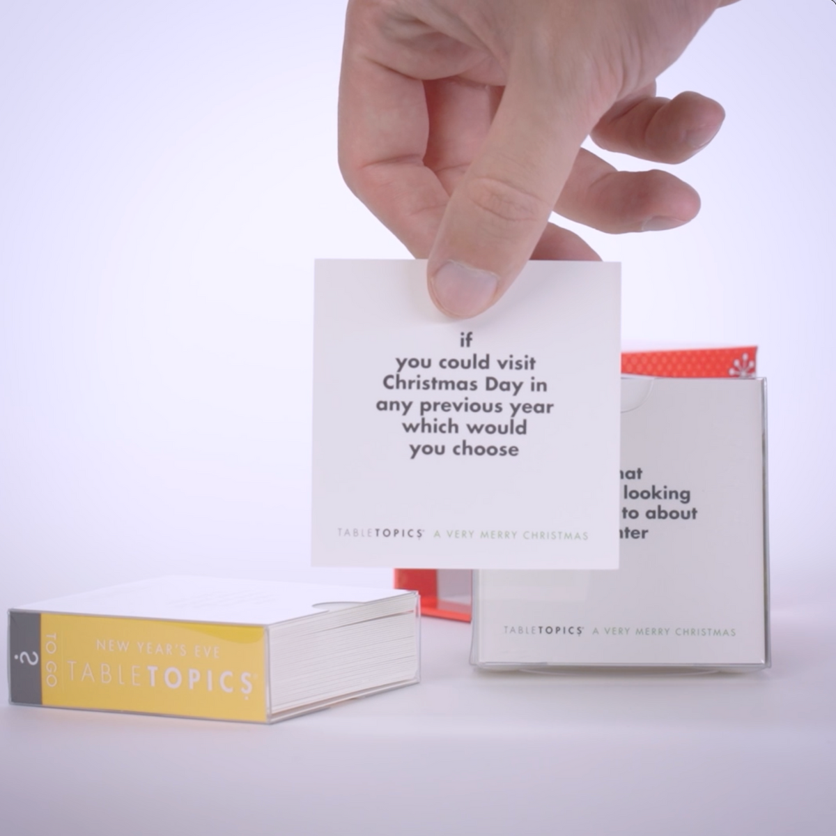 Hand pulling conversation cards from TableTopics Holiday Conversation Pack and showing the questions