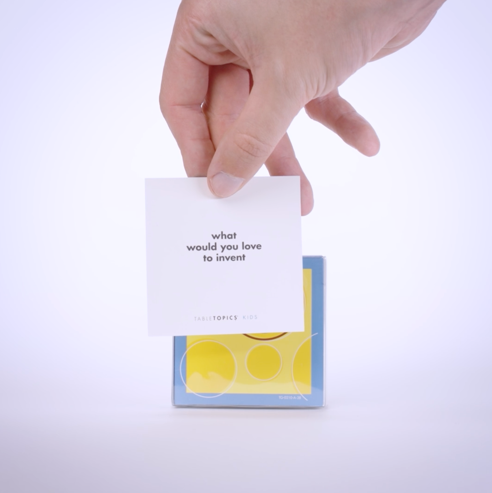 Hand pulling conversation cards from TableTopics Kids To Go and showing the questions