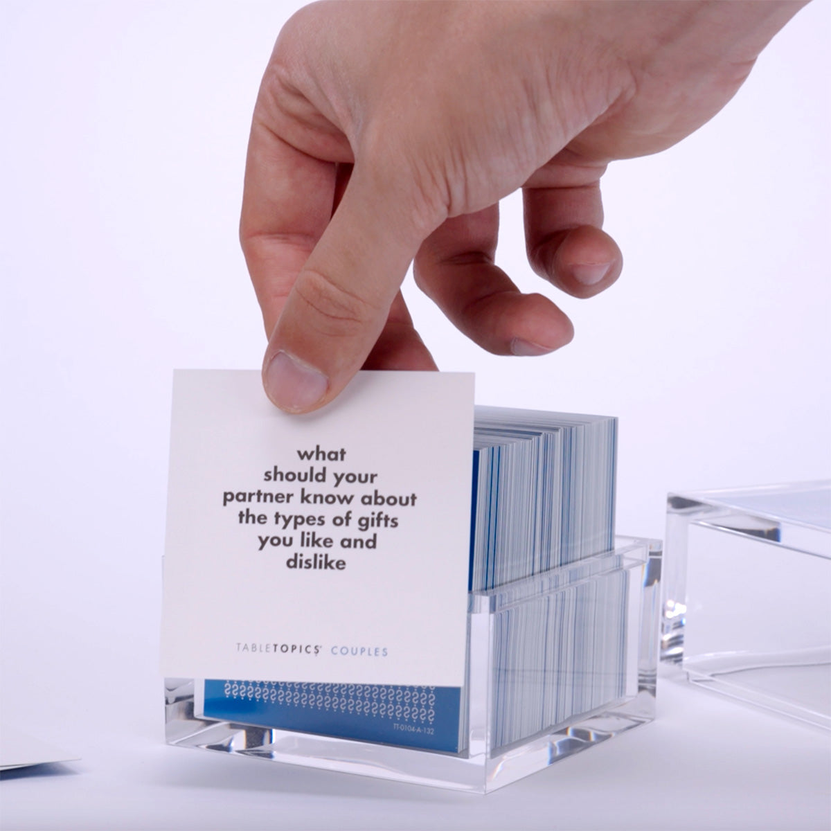 Hand pulling out TableTopics Couples cards from the container and showing the questions