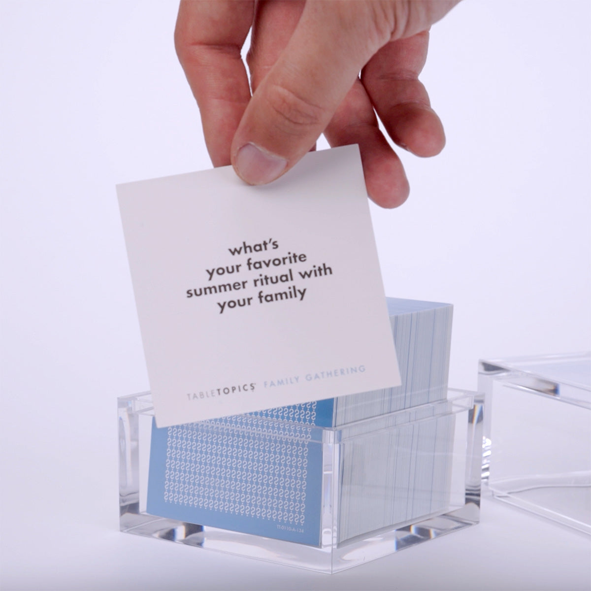 Hand pulling out TableTopics Family Gathering cards from the container and showing the questions