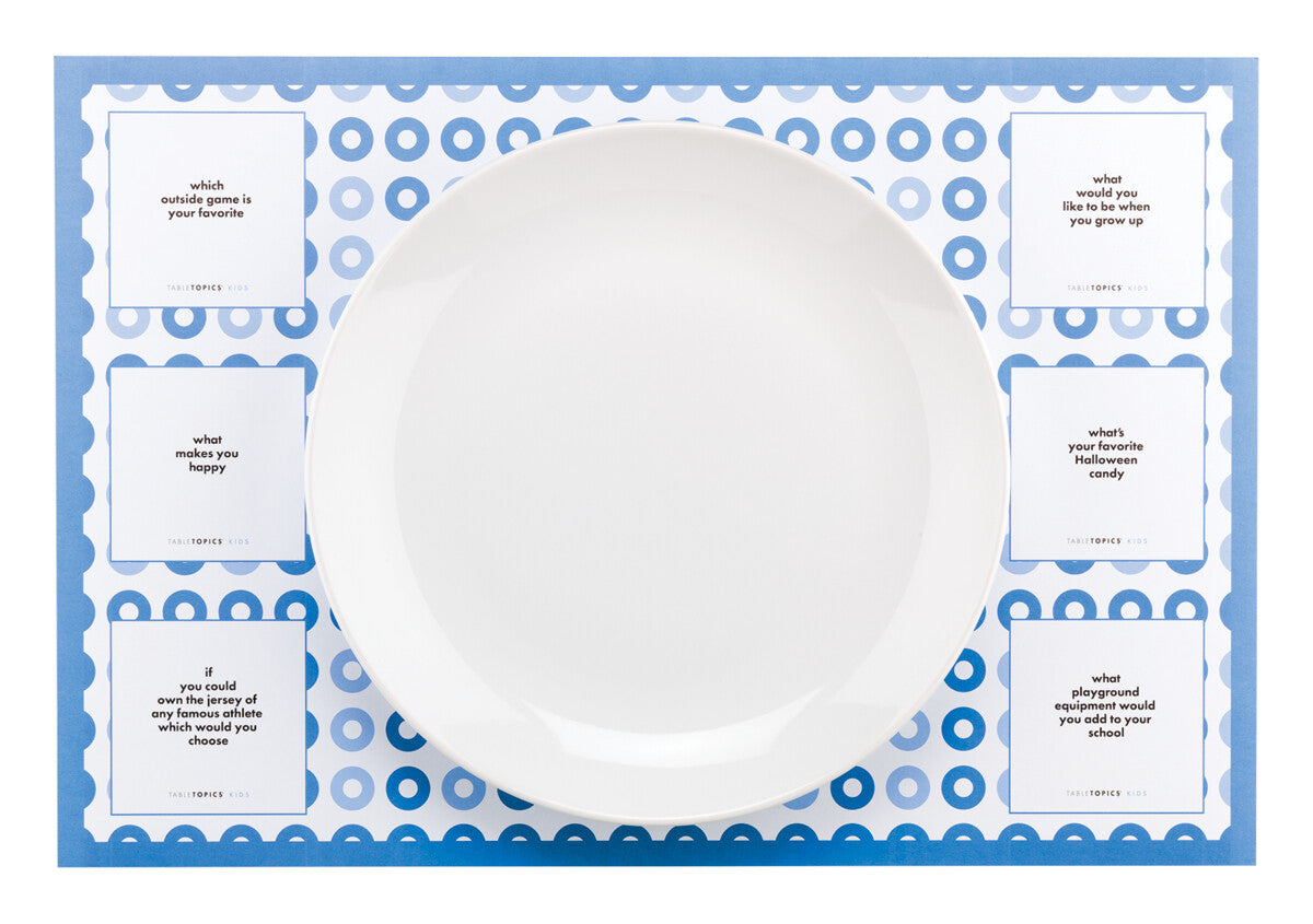 TableTopics Kids Paper Placemat with a plate on top. There are 6 conversation starter questions on the placemat.